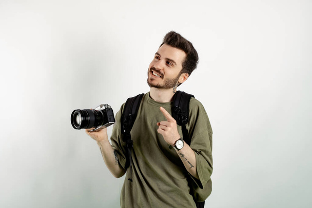 Caucasian man wearing khaki tee posing isolated over white background smiling man pointing left corner with index finger and looking. - Photo, Image