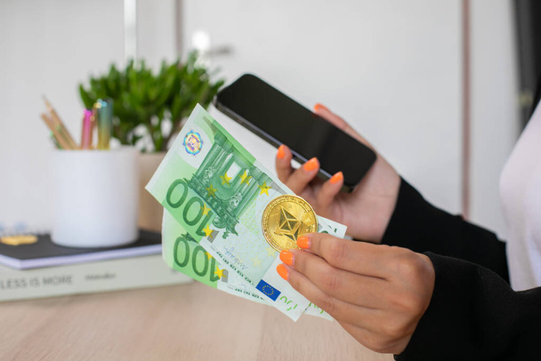 Euro laskut ja kryptovaluutta naisten käsissä puhelimen työpaikalla. Laadukas kuva - Valokuva, kuva