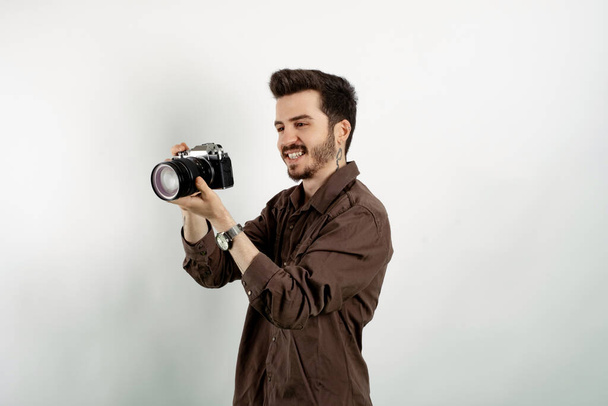 Hezký mladý muž na sobě ležérní oblečení pózovat izolované přes bílé pozadí pózování s jeho dslr fotoaparát a jeho profesionální fotografické vybavení. - Fotografie, Obrázek