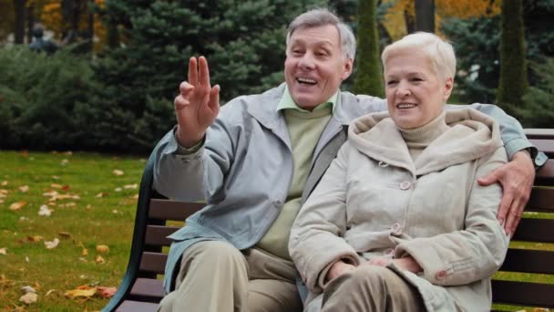 Elderly happy family couple caucasian woman man sit on bench together in autumn park married senior old partners have lovely carefree conversation pleasant chatter talk gossip rest free time outdoors - Footage, Video