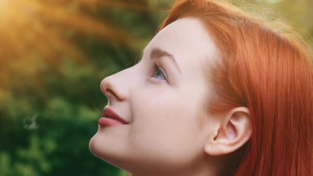 Közelkép női ihlette csinos profil arc vonzó modell tizenéves gyönyörű vörös hajú lány áll kívül napsugarak naplemente háttér fiatal álmodozó élvezze sugarak nő pózol szabadban az esti napfényben - Felvétel, videó