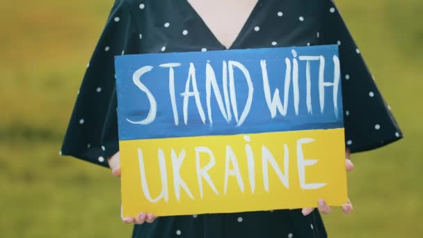 Close up cardboard plate with written inscription stand with Ukraine unknown female activist patriot hold demonstrating banner drawing blue yellow colors request help sends opposition political phrase - Footage, Video