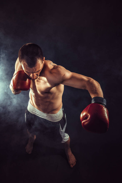 Muscular kickbox or muay thai fighter punching in smoke.  - Photo, image