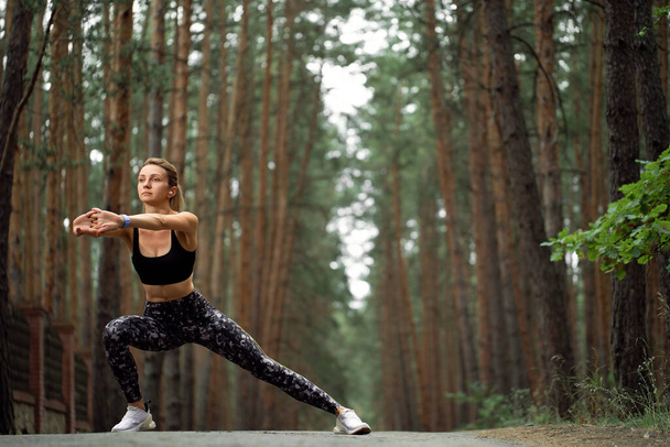 Women stretching arms and breathing fresh air in middle of pinewood forest while exercising. Workouts and Lifestyles concept. Happy life and Healthcare theme. Nature and Outdoors theme.  - Foto, Imagen