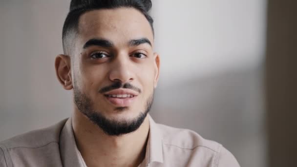 Dromen Arabische knappe jonge man agent werknemer diep in gedachten kijk weg draai hoofd op camera gelukkig man menselijk gezicht vriendelijk zakenman millennial twintiger jaren man glimlachen met tanden glimlach close-up portret - Video