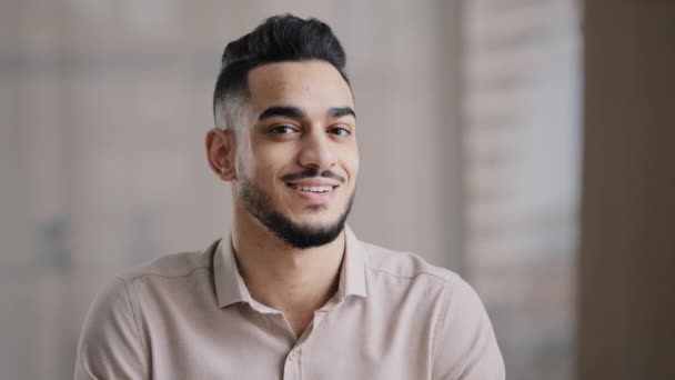 Ritratto di sicuro calmo giovane uomo arabo etnico maschio bello brunetta ragazzo girare la testa a macchina fotografica felice maschio umano barbuto faccia positivo sorridente ispanico millenario uomo d'affari mostra dente salute sorriso - Filmati, video