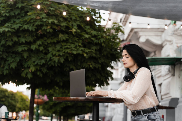Mujer con pigmentación de la piel vitiligo en las manos que trabajan en el ordenador portátil en línea al aire libre en la cafetería. Enfermedad estacional - Foto, Imagen