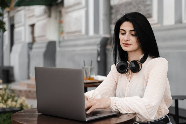 Mujer con pigmentación de la piel vitiligo en las manos que trabajan en el ordenador portátil en línea al aire libre en la cafetería. Enfermedad estacional - Foto, imagen