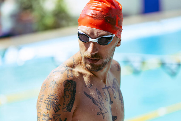 Look of champion. Closeup young handsome man, professional swimmer in goggles and swimming cap getting ready to swim, outdoors. Sport, power, energy, style, hobby concept. - Foto, Imagem