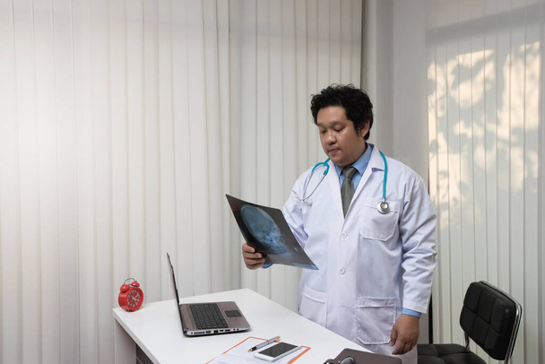 Asiatique mâle médecin analyse crâne X-ray au bureau - Photo, image
