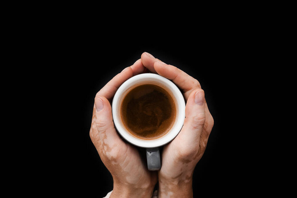 Manos con pigmentación de la piel de vitiligo sosteniendo la taza de café sobre fondo negro de cerca. Estilo de vida con enfermedades estacionales de la piel - Foto, imagen