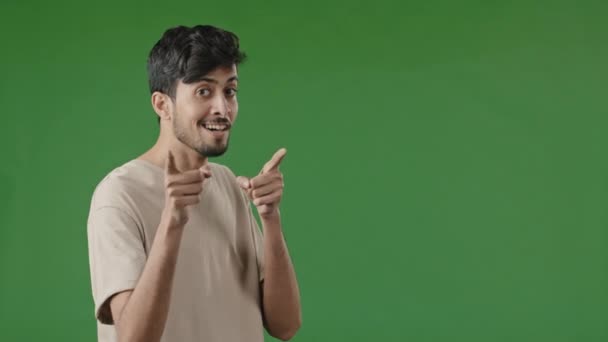 Позитивний усміхнений арабський молодий хлопець стоїть в зеленій студії, показуючи, як ти жестикулюєш, прикидаючись стріляючими пістолетами, роблячи вибір з дозволу рук схвалення символ схвалення гарної ідеї знак поваги
 - Кадри, відео