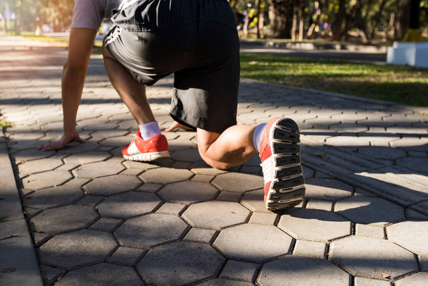 Pronti a partire! Close up foto angolo basso ritagliato di scarpa di atleta uomo in corsa iniziare posa su strada nel parco
. - Foto, immagini
