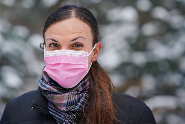 Young woman in winter jacket with pink disposable single use face virus mask - Фото, зображення