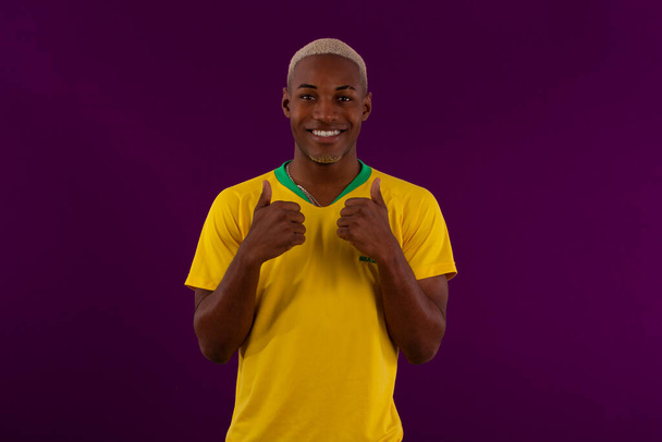 Uomo brasiliano dalla pelle nera con camicia della squadra di calcio brasiliana in studio foto - Foto, immagini