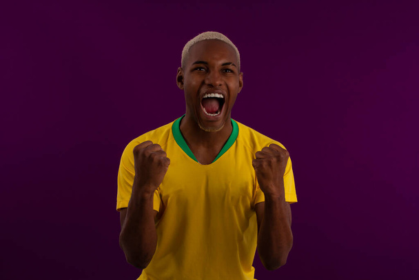 Homem brasileiro de pele preta com camisa do time de futebol brasileiro em foto de estúdio - Foto, Imagem