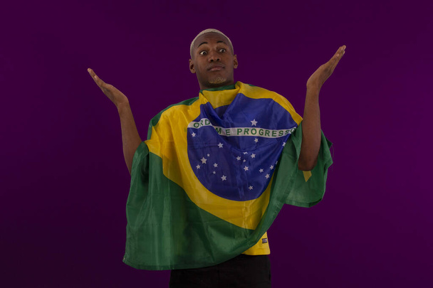 Uomo dalla pelle nera che tiene la bandiera del Brasile e indossa la camicia della squadra di calcio brasiliana in studio foto - Foto, immagini