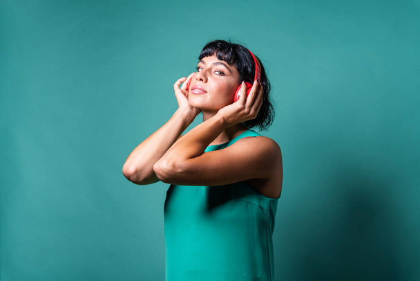 щаслива молода жінка слухає музику на бездротових навушниках з радіо усміхненої дівчини в гарнітурі технології жіночої в червоному гаджеті навушників
  - Фото, зображення