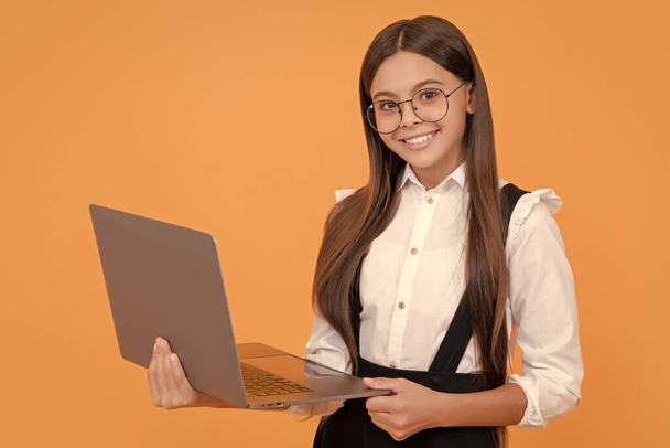 šťastný dospívající dívka ve škole uniforma a brýle studium na notebooku, příležitostné učení. - Fotografie, Obrázek