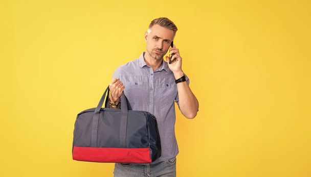 ビジネスマンは旅行袋を持ってスマートフォンで話す。男はスポーツバッグを持って会話してる。電話交渉だ。携帯技術のような声の接触。携帯電話で話して。コミュニケーション. - 写真・画像