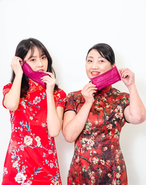 Portrait of asian women both wearing traditional cheongsam qipao dress wearing facemask during isolated on white background. - Photo, Image
