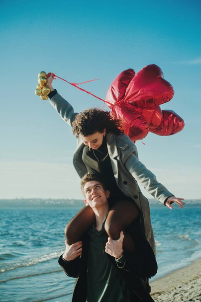 Ευτυχισμένο ζευγάρι με κόκκινα μπαλόνια στην παραλία - Φωτογραφία, εικόνα