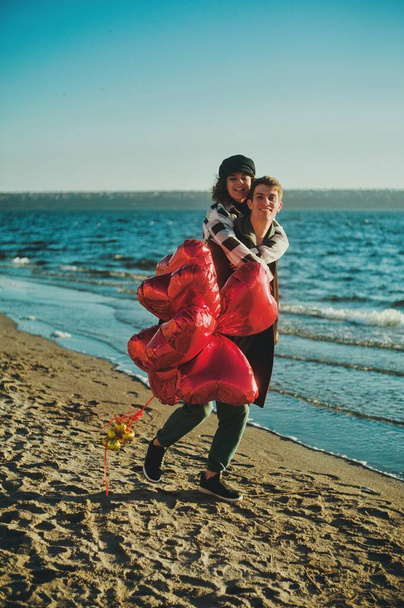 Happy running couple with a red heart balloons on the beach - Zdjęcie, obraz