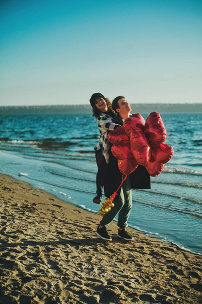 Щаслива бігова пара з червоними кульками серця на пляжі
 - Фото, зображення