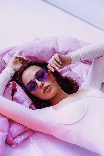 Ukrainian young girl in sunglasses and white bodysuit and jacket on light background. Female body and style concept. Advertisement or clothes sale design. - 写真・画像