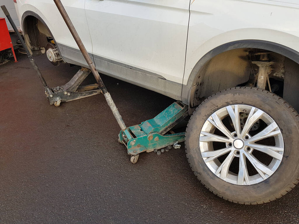 Car lifted with hydraulic floor jack for repairing - Fotoğraf, Görsel