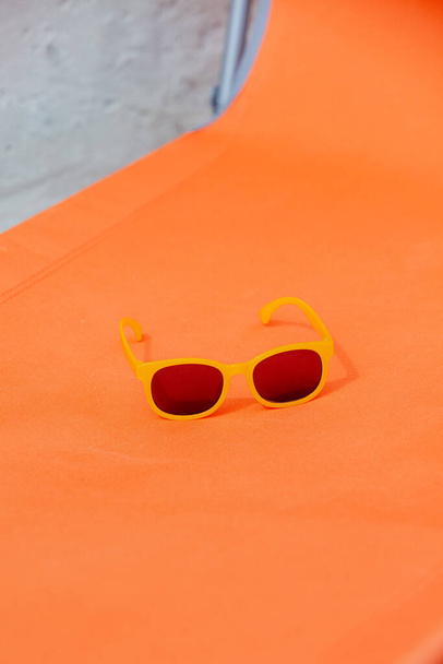 Turuncu güneş yatağında sarı güneş gözlüğü - Fotoğraf, Görsel