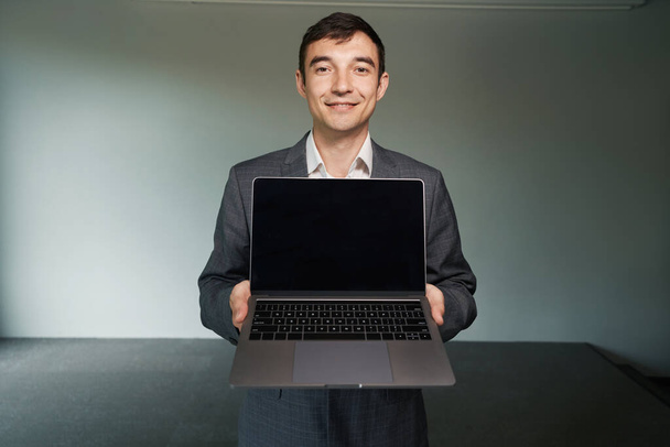 mężczyzna biuro pracownik pokazując laptop dla kamery z uśmiechem na jego twarzy - Zdjęcie, obraz