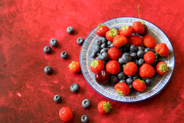 Nyári csendélet friss bogyókkal a kerámia tányérokon. Top view fotó organikus cseresznye, áfonya és eper. Egészséges táplálkozás koncepciója.  - Fotó, kép