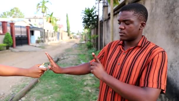 Afrikkalainen poika kieltäytyy polttamasta hänelle tarjottua savuketta, ottaa savukkeen ja rikkoo sen kahtia.. - Materiaali, video