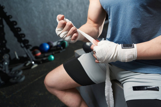 Cropped photo of professional male boxer wrapping elastic bandage around right wrist - Valokuva, kuva
