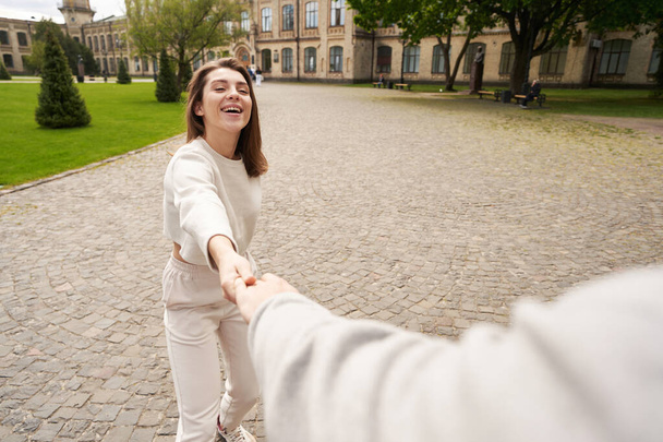 Ακολούθησέ με φωτογραφία της ευτυχισμένης γυναίκας να τραβάει το χέρι του φίλου της και να χαμογελάει ενώ οδηγεί τον άντρα στη λεωφόρο της πόλης - Φωτογραφία, εικόνα