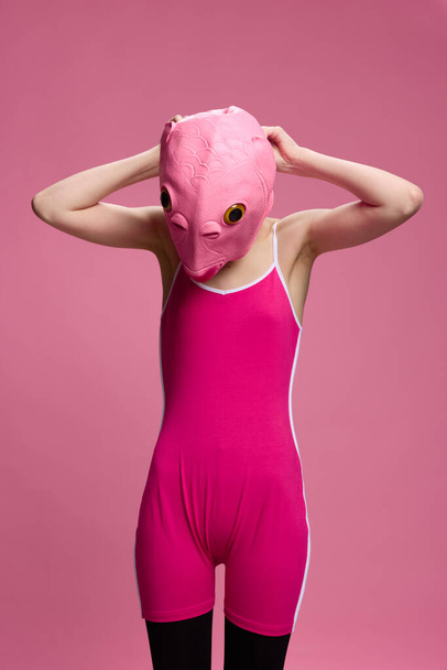 Mulher muito estranha em uma máscara de peixe de silicone rosa para Halloween, imagem louca em roupas rosa. Foto de alta qualidade - Foto, Imagem