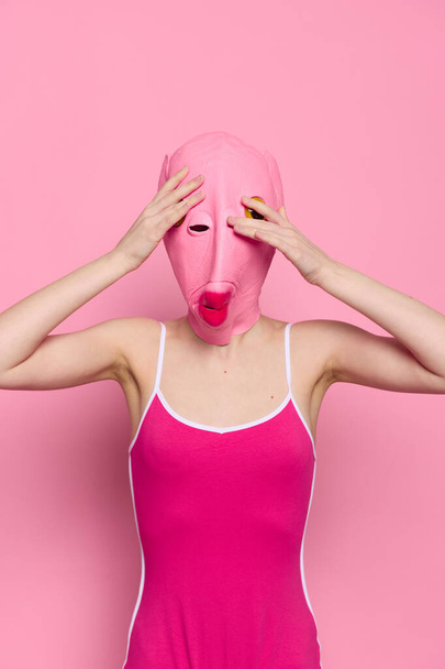 Божевільна жінка в костюмі голови рожевої риби позує на рожевому студійному фоні, провокаційний костюм на Хеллоуїн. Високоякісна фотографія - Фото, зображення