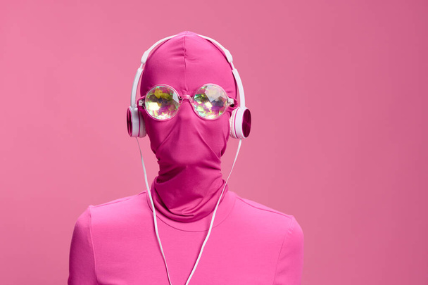 Luova fani taide kuva nuori nainen cyberpunk bloggaaja vaaleanpunainen tausta yllään vaaleanpunainen kokokasvoinen naamio hehkuva pyöreä lasit ja kuulokkeet. Laadukas kuva - Valokuva, kuva