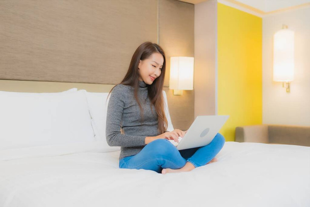 Retrato hermosa joven mujer asiática uso de ordenador portátil en la cama en el interior del dormitorio - Foto, imagen