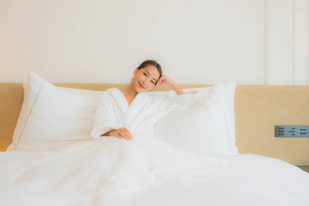 Portret mooie jonge aziatische vrouw ontspannen glimlach vrije tijd op bed in slaapkamer interieur - Foto, afbeelding