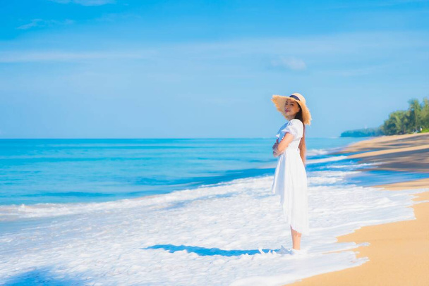 Πορτρέτο όμορφη νεαρή Ασιάτισσα γυναίκα χαλαρώστε χαμόγελο αναψυχής γύρω από θάλασσα θάλασσα ωκεανό παραλία με λευκό σύννεφο σε μπλε ουρανό σε ταξιδιωτικές διακοπές - Φωτογραφία, εικόνα