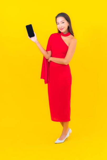 Портрет красива молода азіатка зі смартфоном з кредитною карткою на жовтому фоні
 - Фото, зображення