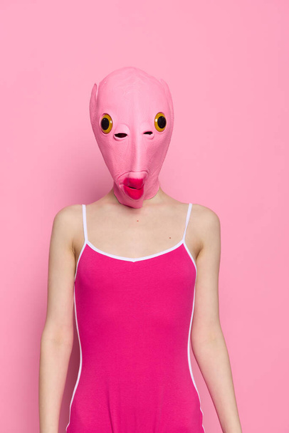 Mulher louca em rosa traje cabeça de peixe posa no fundo do estúdio rosa, traje de Halloween provocante. Foto de alta qualidade - Foto, Imagem