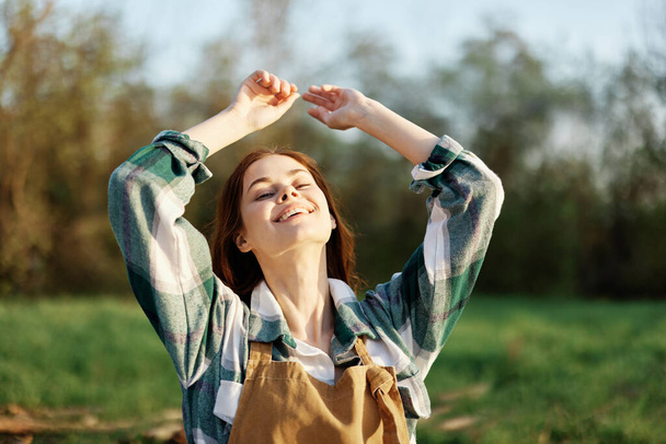 Retrato de una mujer joven con hermoso pelo largo y rojo con una hermosa sonrisa con dientes contra un parque verde en la luz del sol puesta del sol de verano. Foto de alta calidad - Foto, Imagen