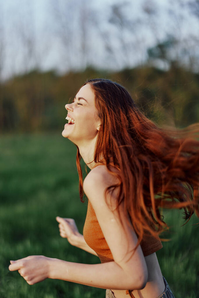 Щаслива атлетична жінка біжить і посміхається в природі в парку, літній захід сонця. Високоякісна фотографія - Фото, зображення