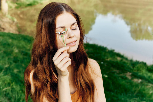 Egy nő, aki egy tavaszi virágot tart a kezében a napfényben, a természetvédelemben és az ökológiában. Kiváló minőségű fénykép - Fotó, kép