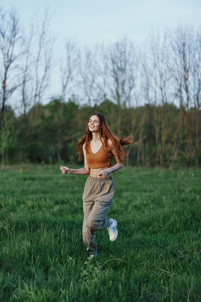 Жінка біжить в парку на зеленій траві під час тренування. Високоякісна фотографія - Фото, зображення