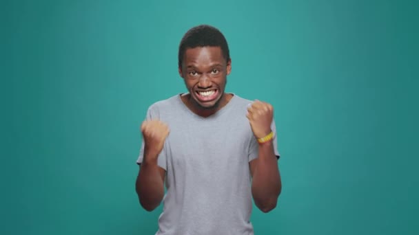 African american man celebrating achievement and success, feeling happy and pleased about big win. Confident excited person cheering after hearing good successful news, doing victory celebration. - Filmati, video