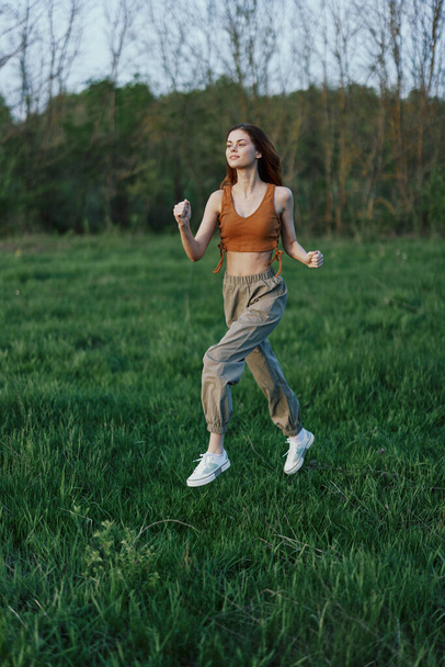 Una mujer atlética corre y entrena su cuerpo antes de la temporada de verano en el parque. Foto de alta calidad - Foto, Imagen